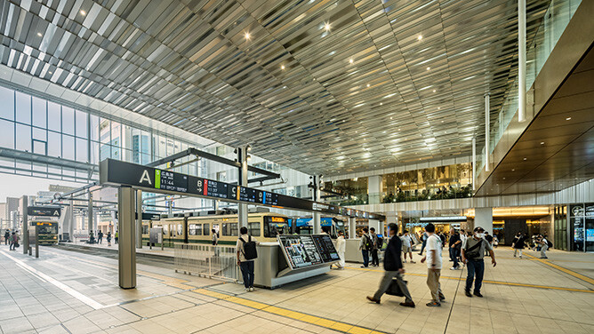 広島駅構内の路面電車乗り場。高い天井のコンコースに案内サインやホームが整備され、多くの利用者が行き交う様子。