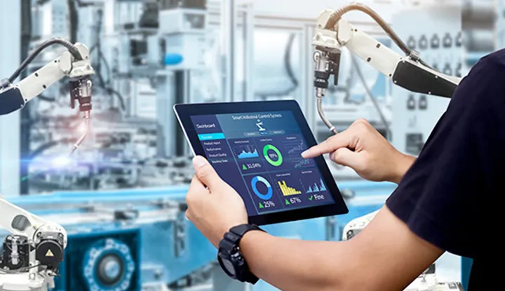 産業用ロボットが稼働する生産設備で、タブレット端末に表示されたデータを確認するイメージ