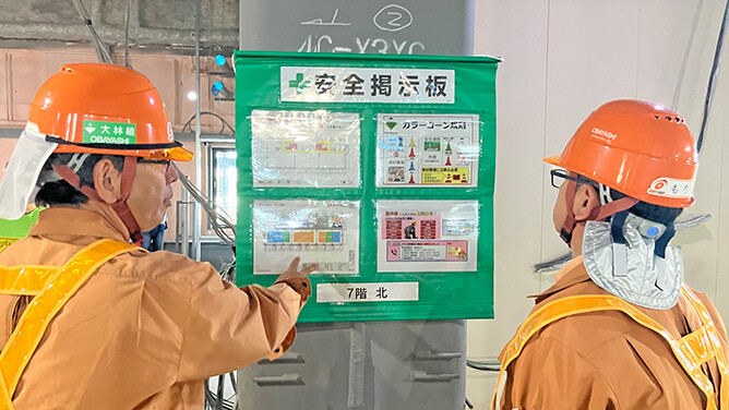 Workers at a construction site reviewing safety information posted on a safety notice board as part of daily health and safety management activities.