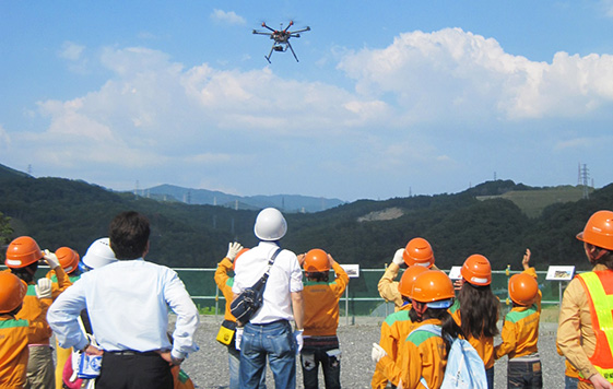 土量の計測に使用するドローン（小型無人機）の実演を興味深く見つめる子どもたち