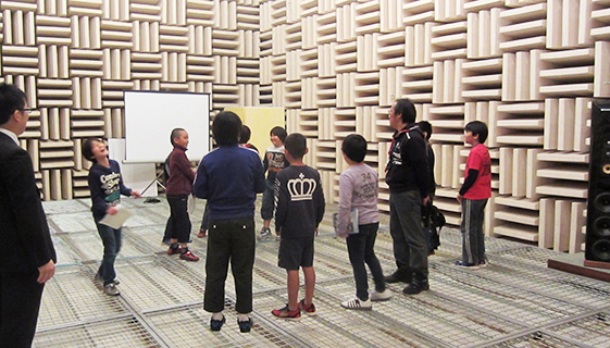 音響実験施設（無響室）で、音の響きを確認するために校歌を歌う子どもたち