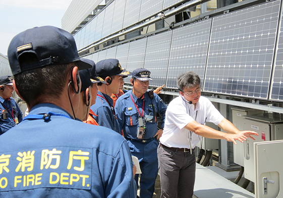 約770枚の太陽光パネルが設置された技術研究所本館テクノステーション屋上で、発電設備の説明を?う?林組技術者