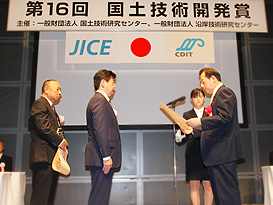太田昭宏国土交通大臣（右）から表彰状を授与される大林組技術担当開発者（中央）と副社長 金井誠（左）